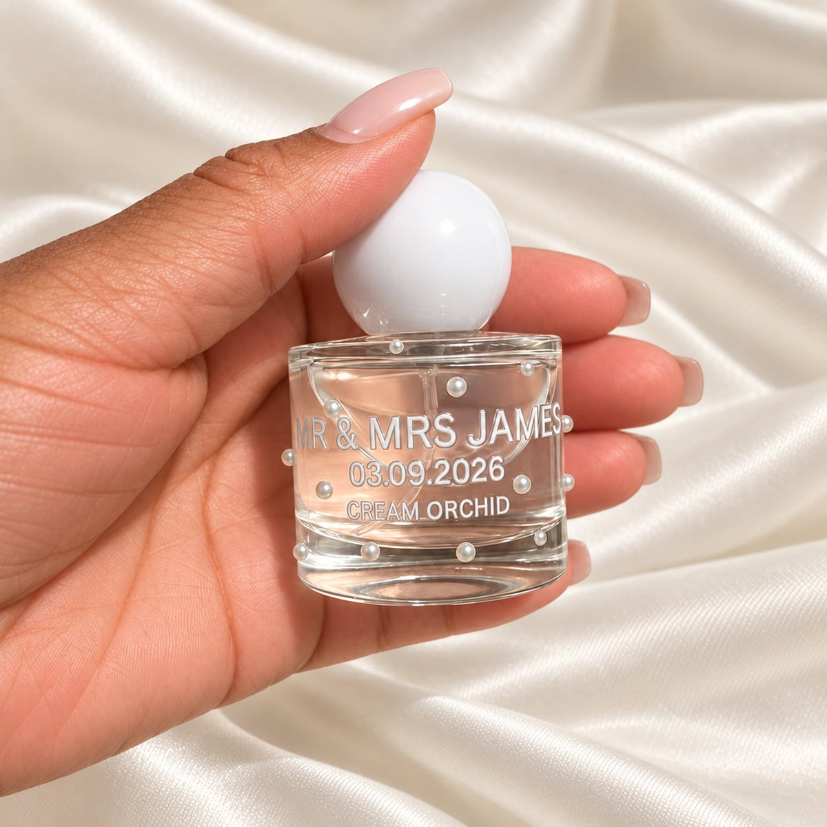30ml Round Perfume Wedding Favours held in a neatly manicured hand on ivory satin