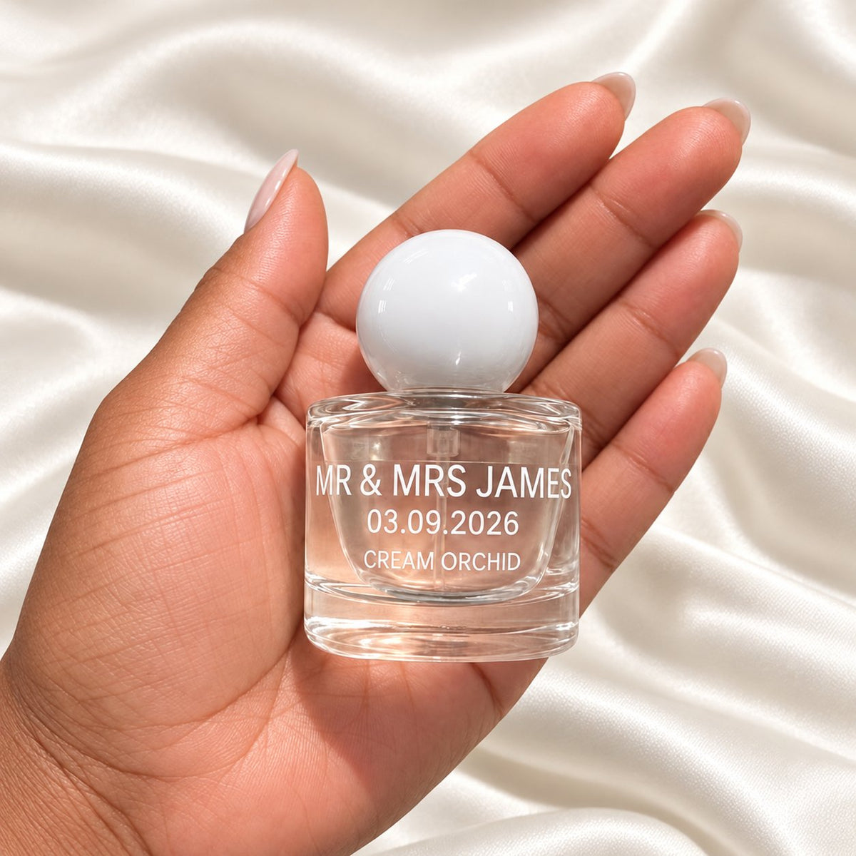 30ml Round Perfume Wedding Favours held in a neatly manicured hand on ivory satin