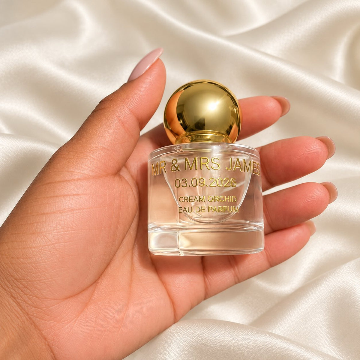 30ml Round Perfume Wedding Favours held in a neatly manicured hand on ivory satin