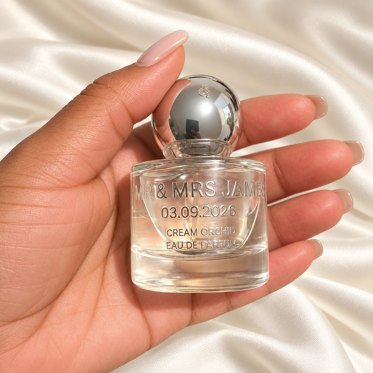 30ml Round Perfume Wedding Favours held in a neatly manicured hand on ivory satin
