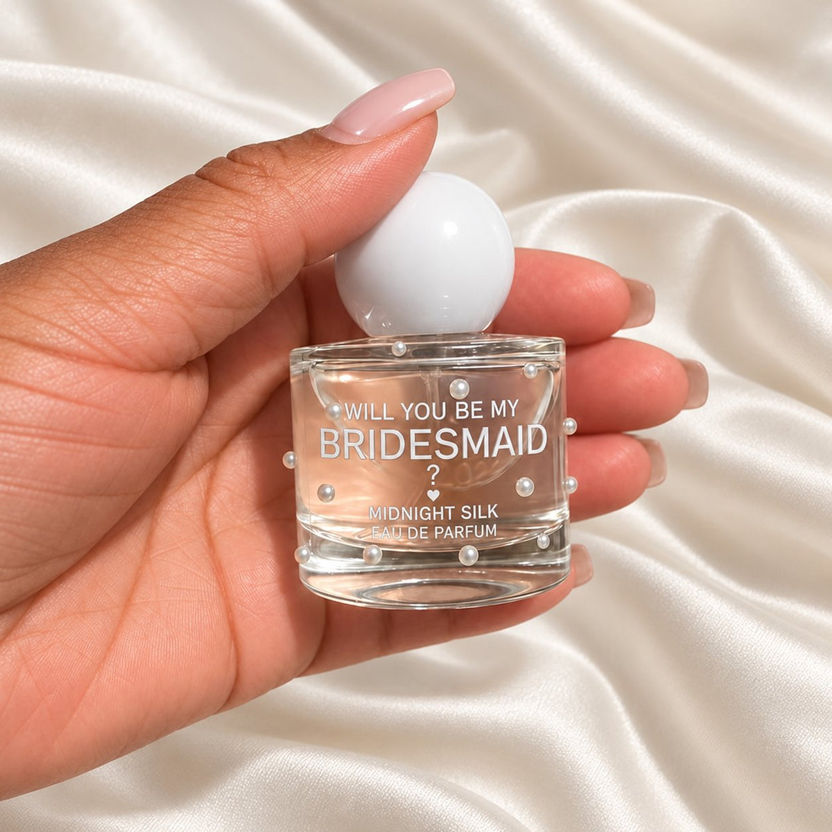 Personalised Bridesmaid Proposal Perfume held in a neatly manicured hand on ivory satin
