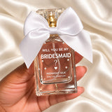 Personalised Bridesmaid Proposal Perfume held in a neatly manicured hand on ivory satin