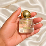 Personalised Bridesmaid Proposal Perfume held in a neatly manicured hand on ivory satin